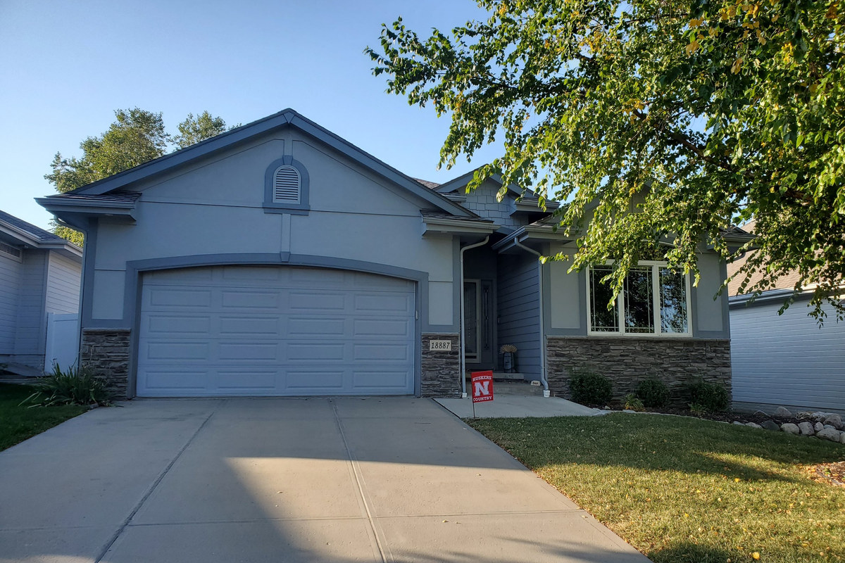 Gray villa home with stone accents and a mature shade tree